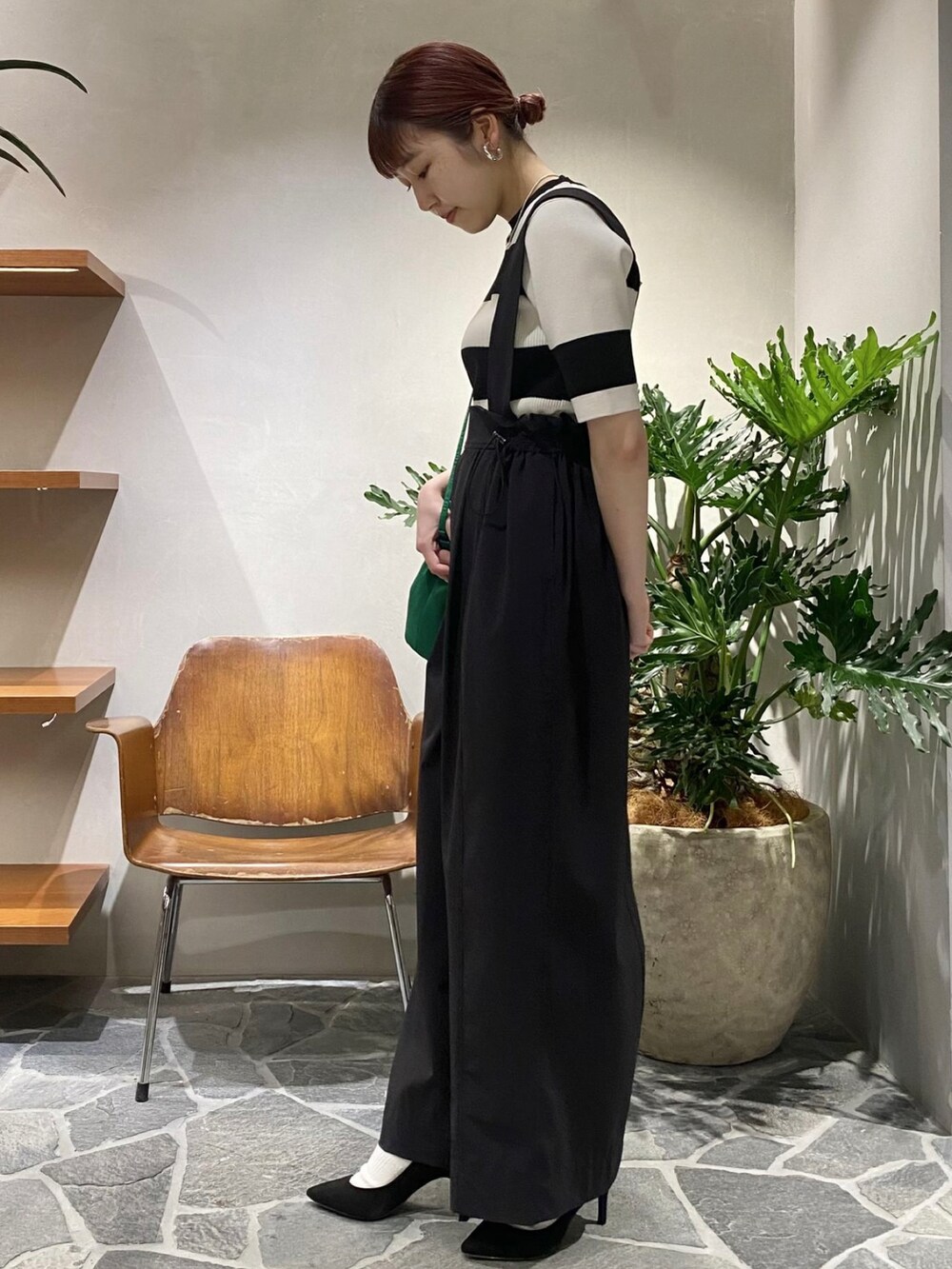 ブラック系のニット/セーター、ブラック系のサロペット/オーバーオール、グリーン系のハンドバッグを着用したレディースの春コーディネートの3枚目の写真