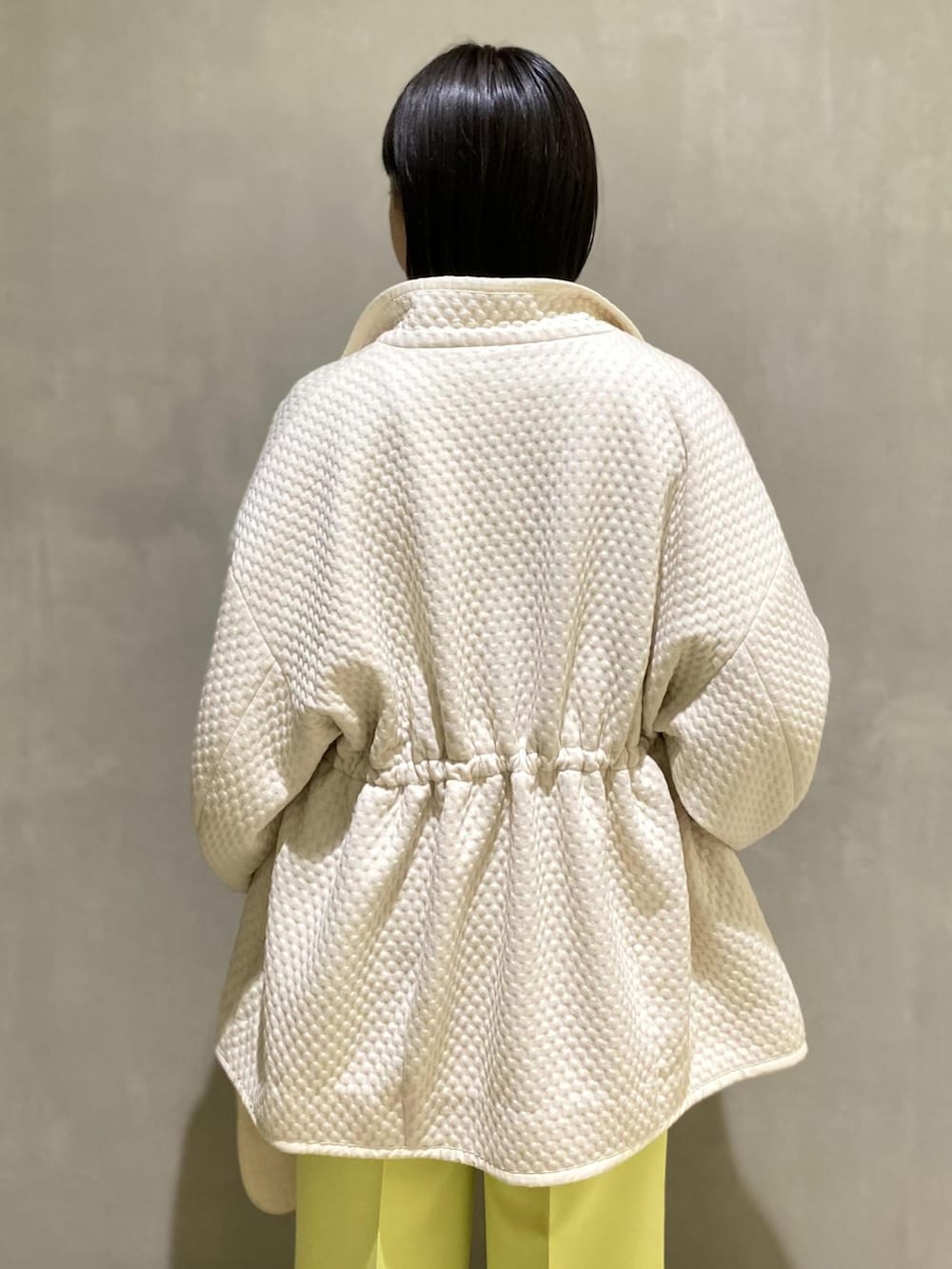 イエロー系のスラックス、ホワイト系のハンドバッグ、ベージュ系のブルゾンを着用したレディースの冬コーディネートの3枚目の写真