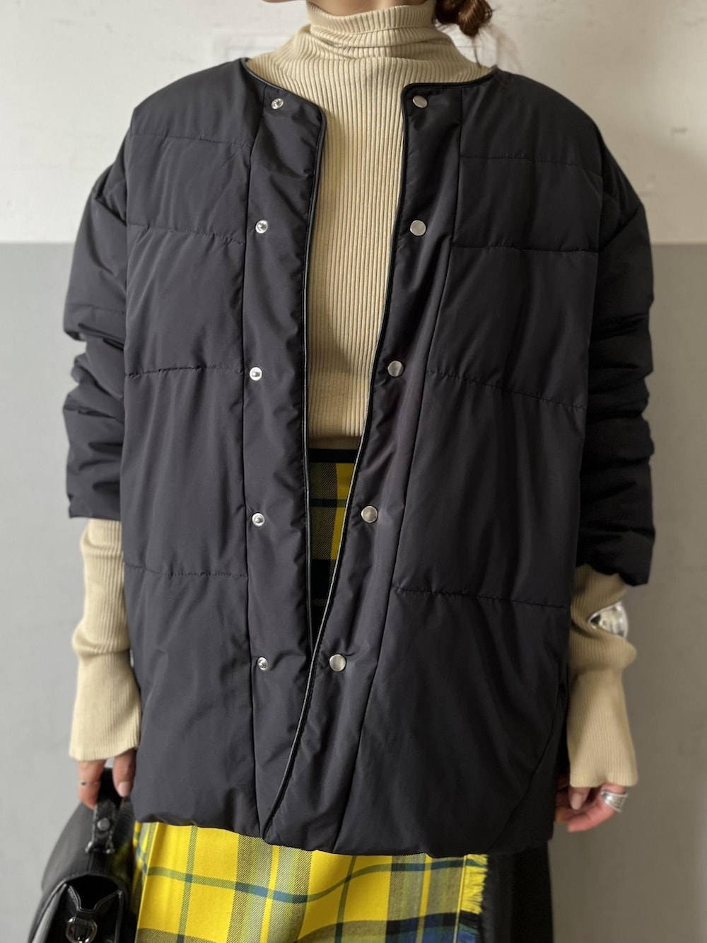 ブラック系のダウンジャケット/コート、ブラック系のショルダーバッグ、イエロー系のスカートを着用したレディースの秋コーディネートの4枚目の写真