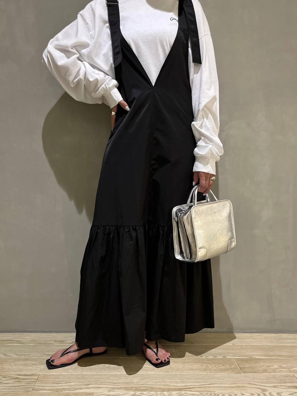 ブラック系のジャンパースカート、ブラック系のサンダル、グリーン系のキャップを着用したレディースの春コーディネートの3枚目の写真