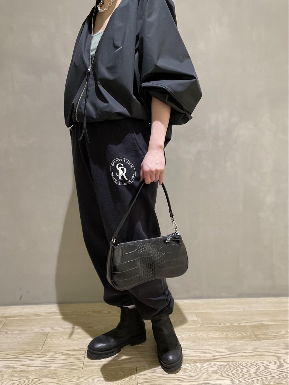 ブラック系のブルゾン、ブラック系のハンドバッグ、ブルー系のタンクトップを着用したレディースの冬コーディネートの5枚目の写真