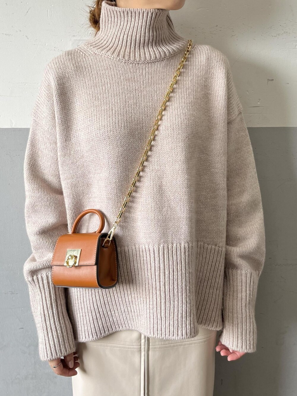 ベージュ系のニット/セーター、イエロー系のショルダーバッグ、ホワイト系のスカートを着用したレディースの夏コーディネートの3枚目の写真