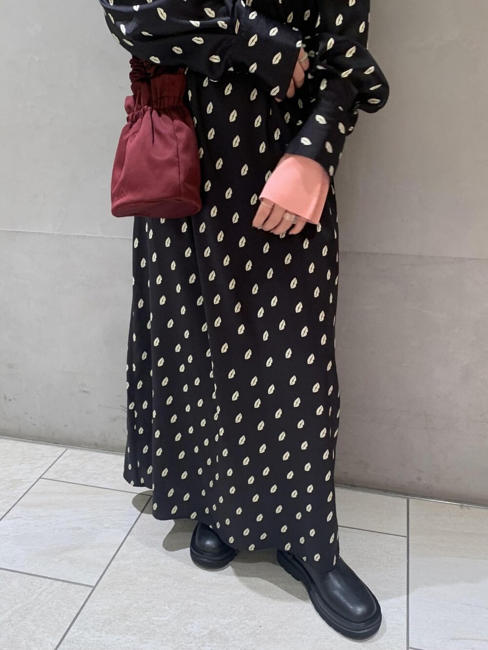 ブラック系のワンピース、ピンク系のニット/セーター、レッド系のバッグを着用したレディースの冬コーディネートの3枚目の写真