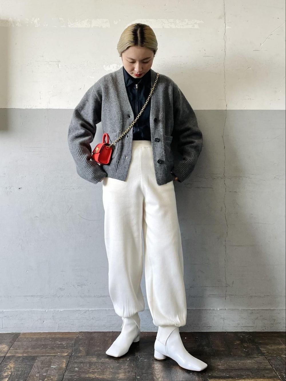 オレンジ系のショルダーバッグ、グレー系のカーディガン/ボレロ、ホワイト系のその他パンツを着用したレディースの冬コーディネートの2枚目の写真