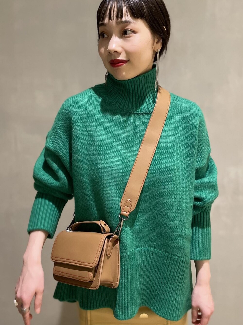 グリーン系のニット/セーター、ベージュ系のスカート、ブラック系のブーツを着用したレディースの夏コーディネートの4枚目の写真