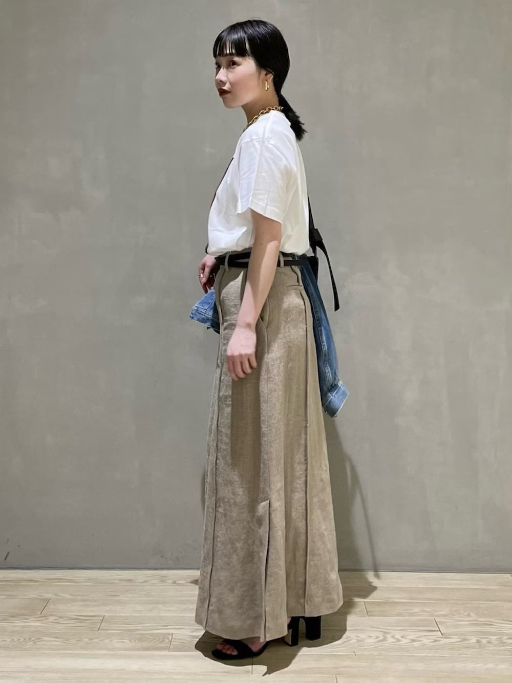 ホワイト系のTシャツ/カットソー、ベージュ系のスカート、ブラック系のサンダルを着用したレディースの春コーディネートの2枚目の写真