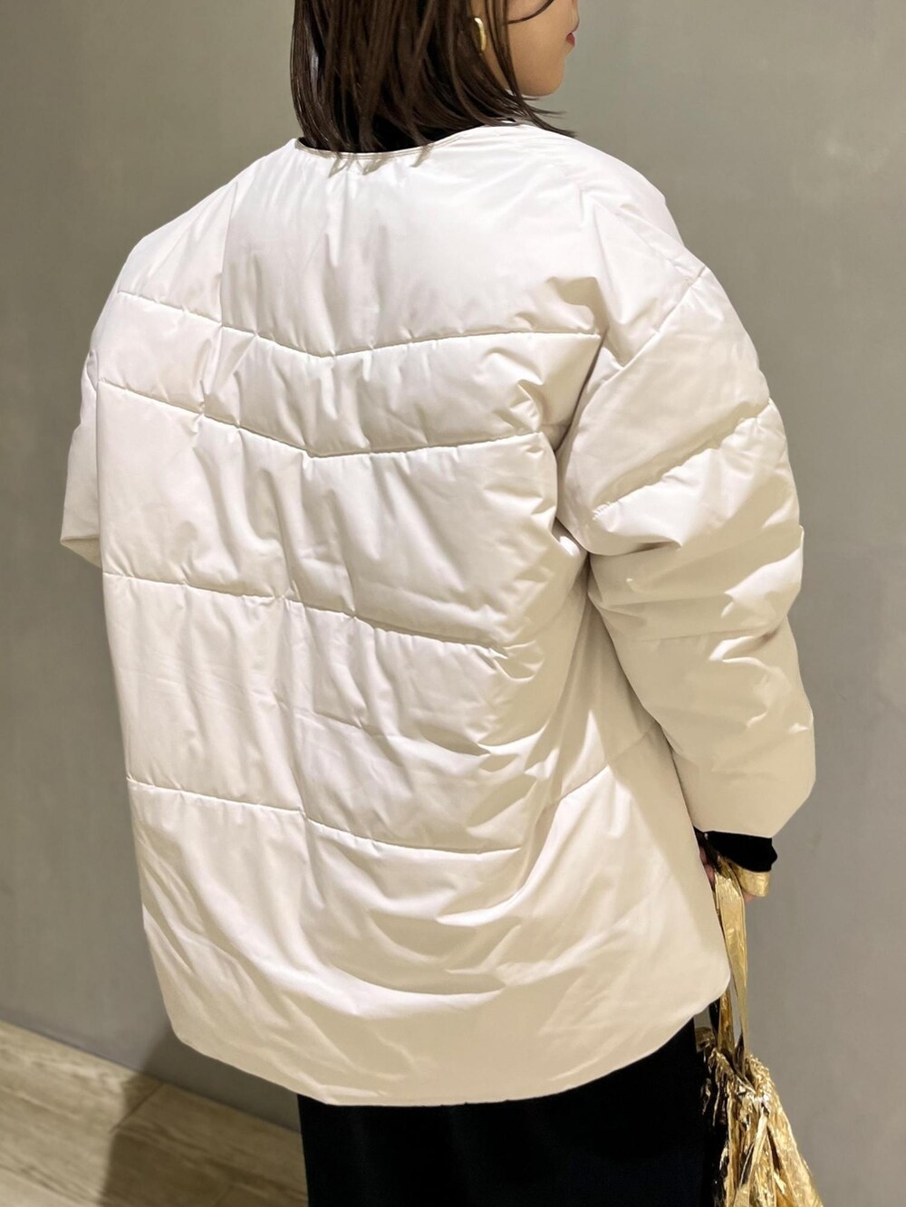 ホワイト系のダウンジャケット/コート、ベージュ系のブーツ、ゴールド系のエコバッグ/サブバッグを着用したレディースの冬コーディネートの3枚目の写真