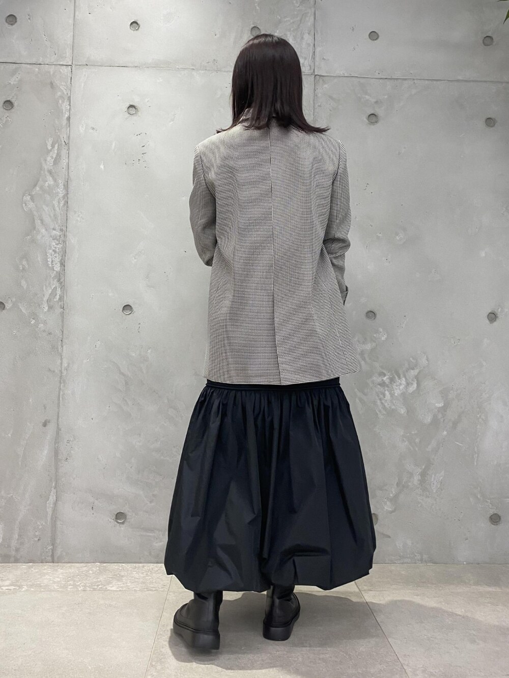 ブラウン系のテーラードジャケット、イエロー系のキャミソール、ブラック系のスカートを着用したレディースの夏コーディネートの2枚目の写真