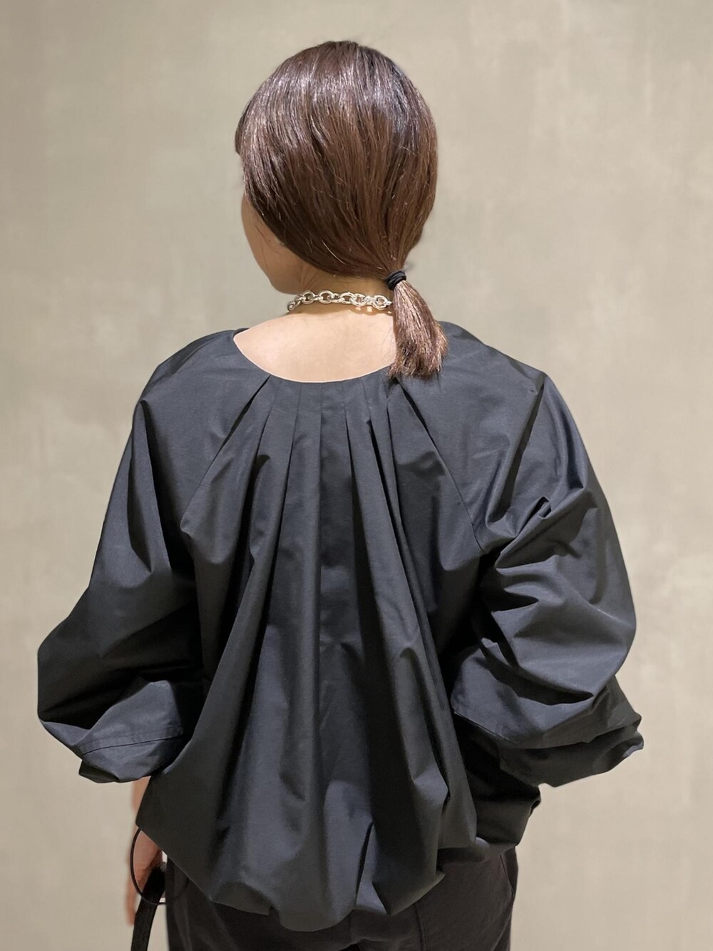 ブラック系のブルゾン、ブラック系のハンドバッグ、ブルー系のタンクトップを着用したレディースの冬コーディネートの3枚目の写真