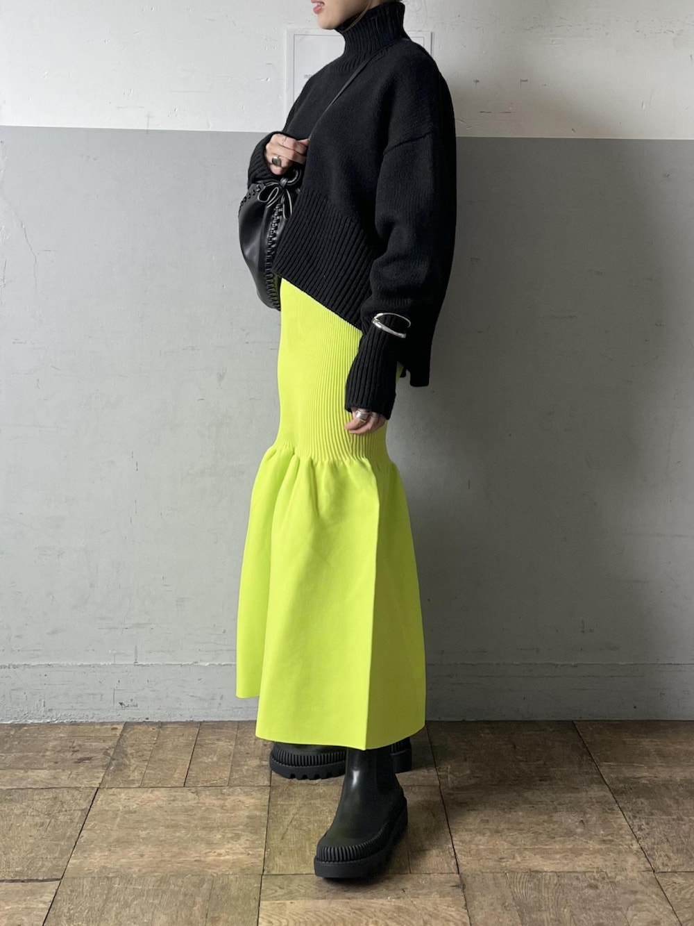 ブラック系のニット/セーター、グリーン系のスカート、ブラック系のブーツを着用したレディースの夏コーディネートの5枚目の写真