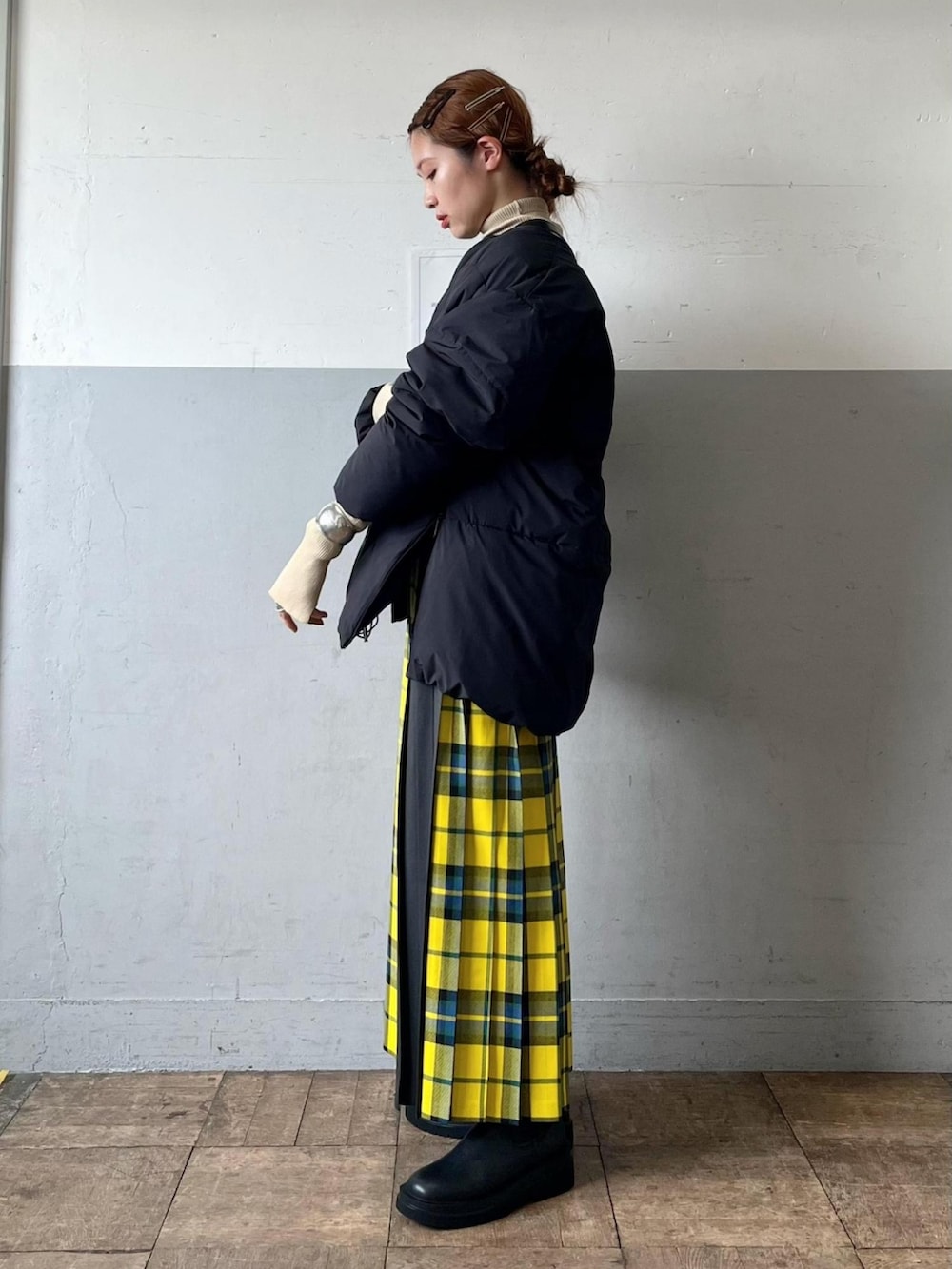 ブラック系のダウンジャケット/コート、ブラック系のショルダーバッグ、イエロー系のスカートを着用したレディースの秋コーディネートの3枚目の写真