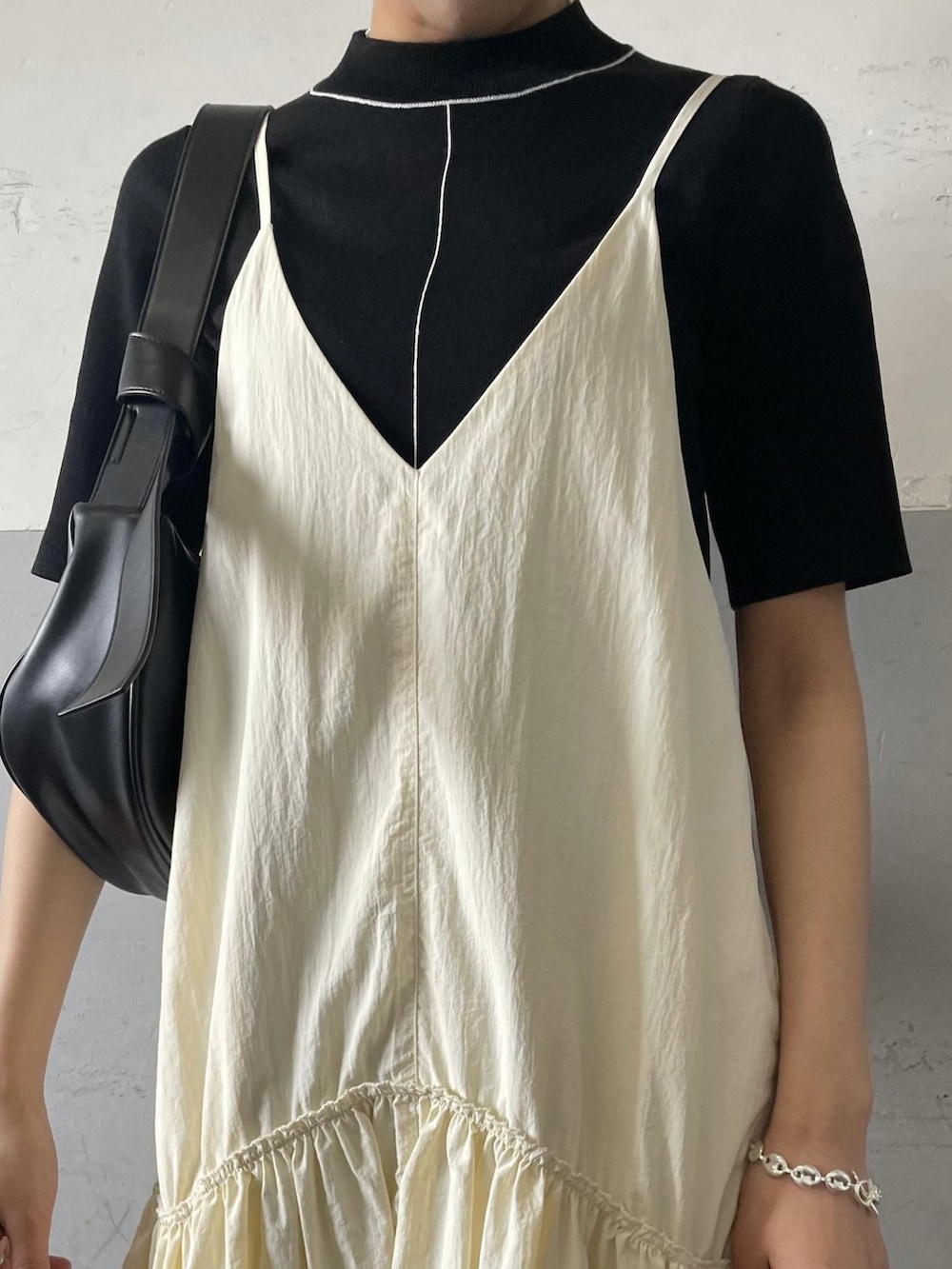 ホワイト系のワンピース、ブラック系のニット/セーター、ブラック系のショルダーバッグを着用したレディースの春コーディネートの4枚目の写真