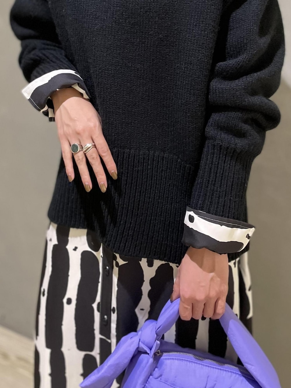 ブラック系のニット/セーター、パープル系のハンドバッグ、ブラック系のワンピースを着用したレディースの夏コーディネートの3枚目の写真