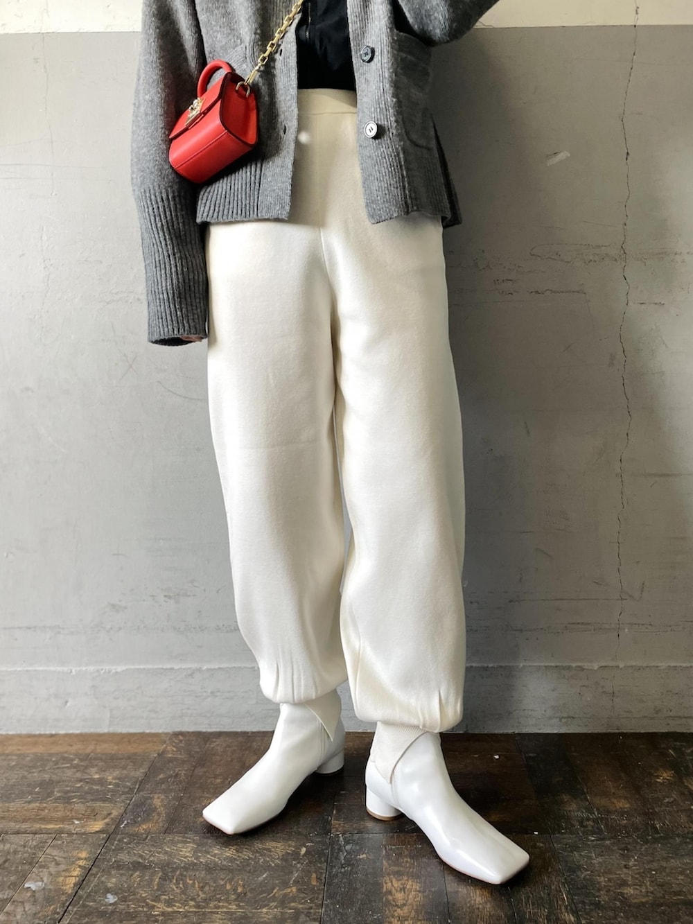 オレンジ系のショルダーバッグ、グレー系のカーディガン/ボレロ、ホワイト系のその他パンツを着用したレディースの冬コーディネートの5枚目の写真