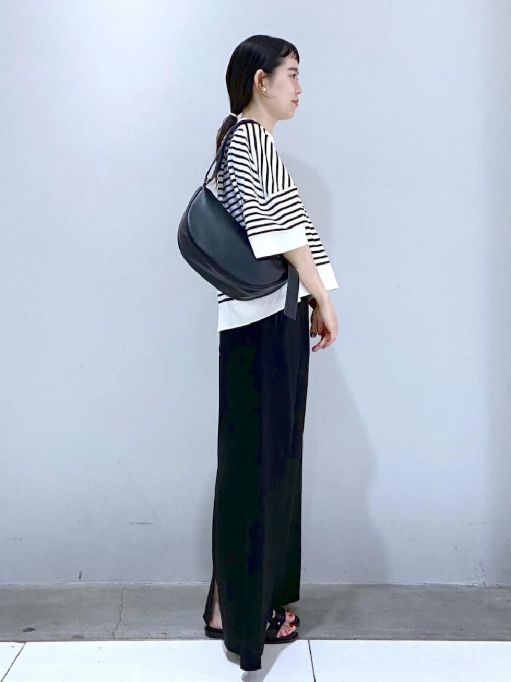 ホワイト系のTシャツ/カットソー、ブラック系のスカート、ブラック系のサンダルを着用したレディースの夏コーディネートの2枚目の写真