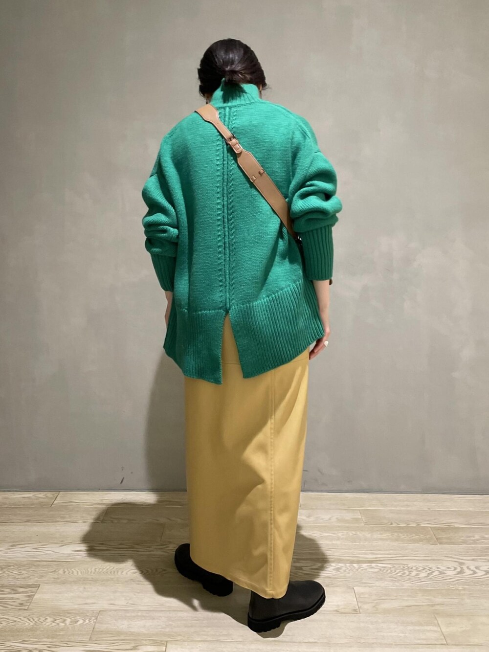 グリーン系のニット/セーター、ベージュ系のスカート、ブラック系のブーツを着用したレディースの夏コーディネートの2枚目の写真