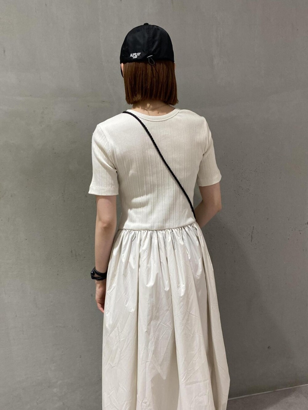 ホワイト系のワンピース、ブラック系のショルダーバッグ、ブラック系のブーツを着用したレディースの夏コーディネートの2枚目の写真