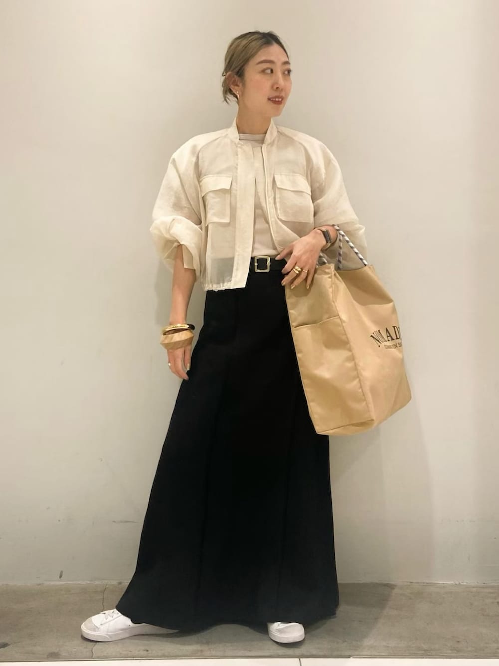 ベージュ系のトートバッグ、ベージュ系のブルゾン、ブラック系のスカートを着用したレディースの春コーディネートの2枚目の写真
