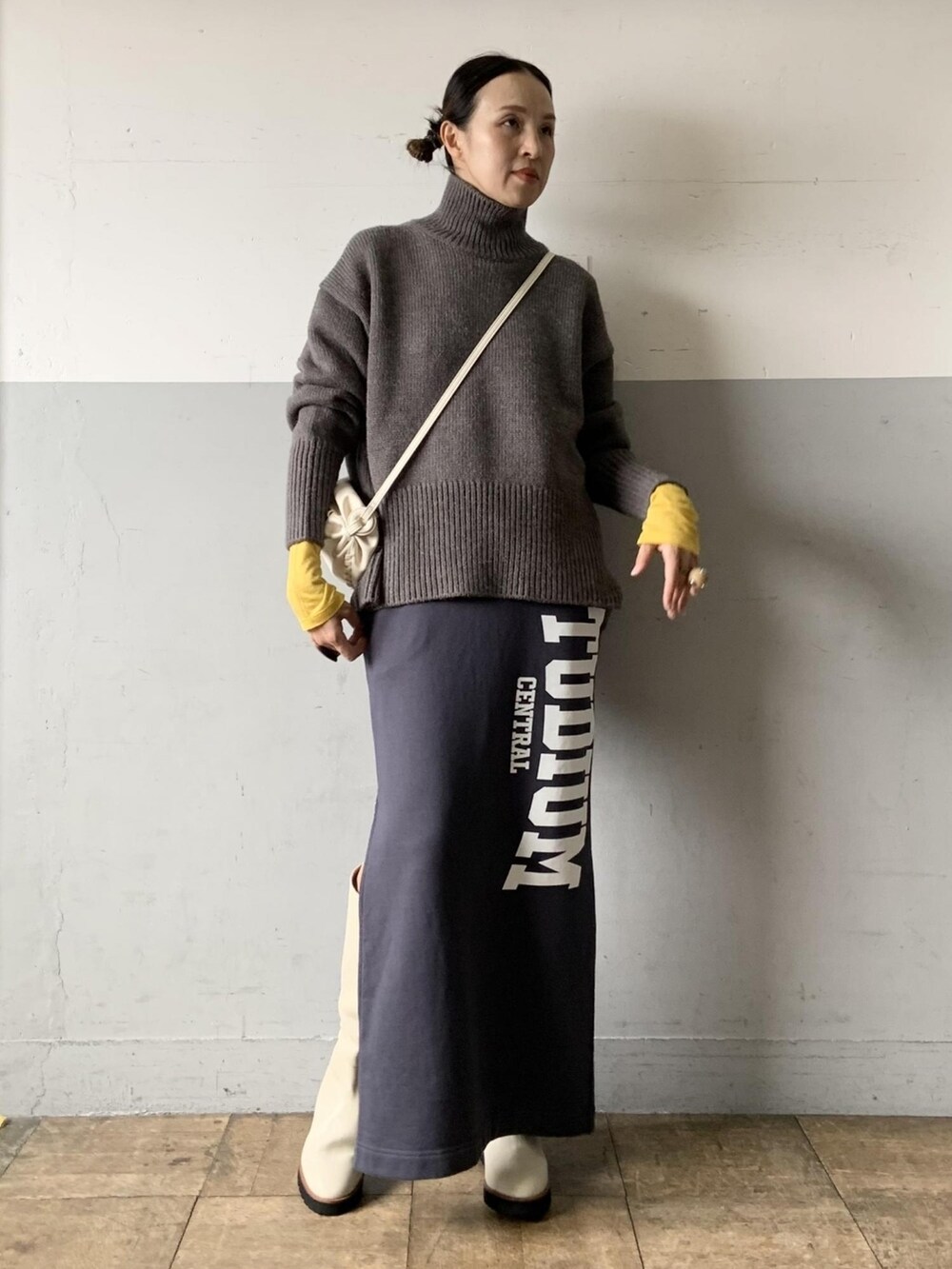 グレー系のニット/セーター、イエロー系のTシャツ/カットソー、ホワイト系のブーツを着用したレディースの夏コーディネートの2枚目の写真