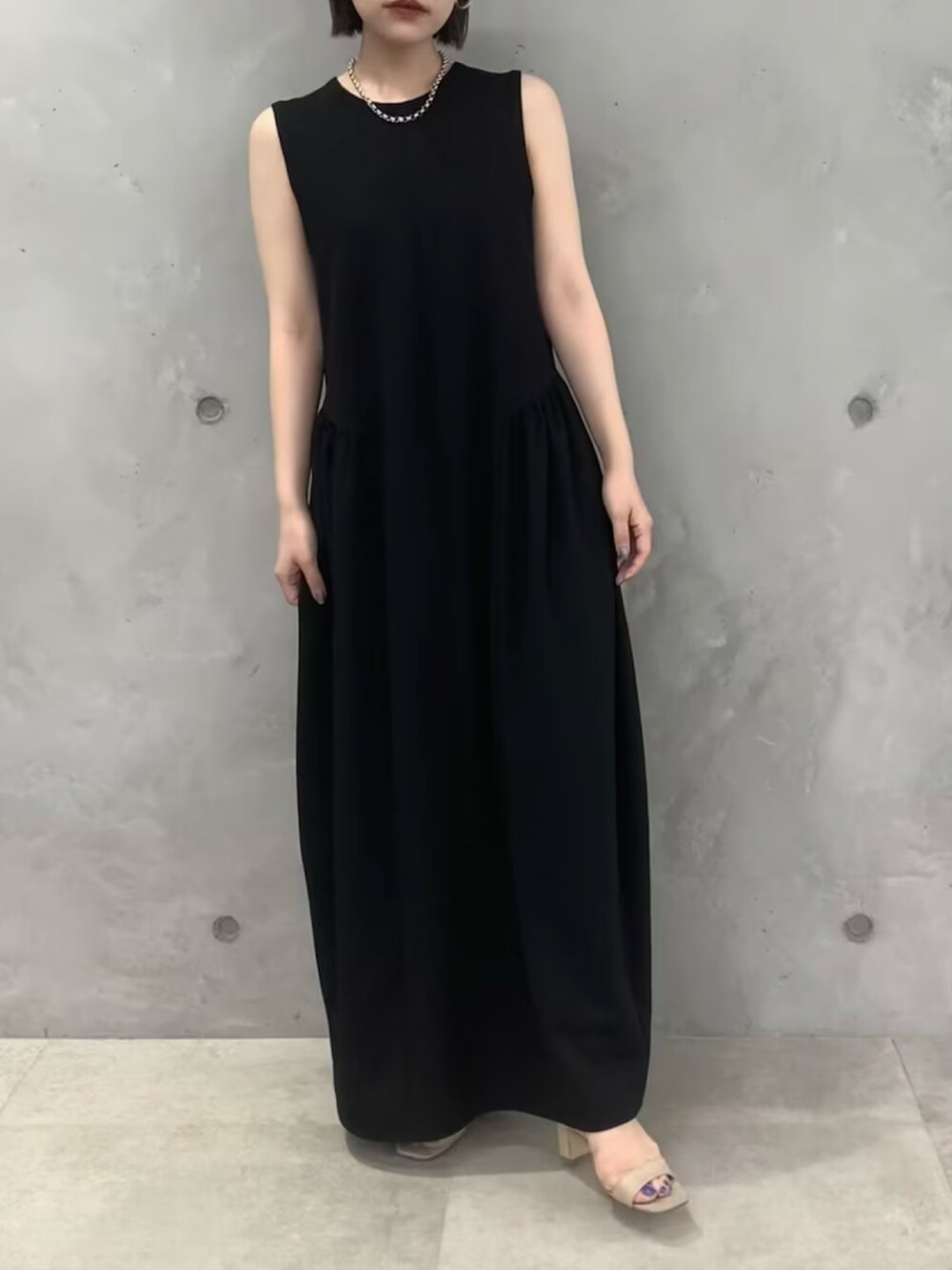 ブラック系のワンピース、ベージュ系のサンダルを着用したレディースの春コーディネートの2枚目の写真