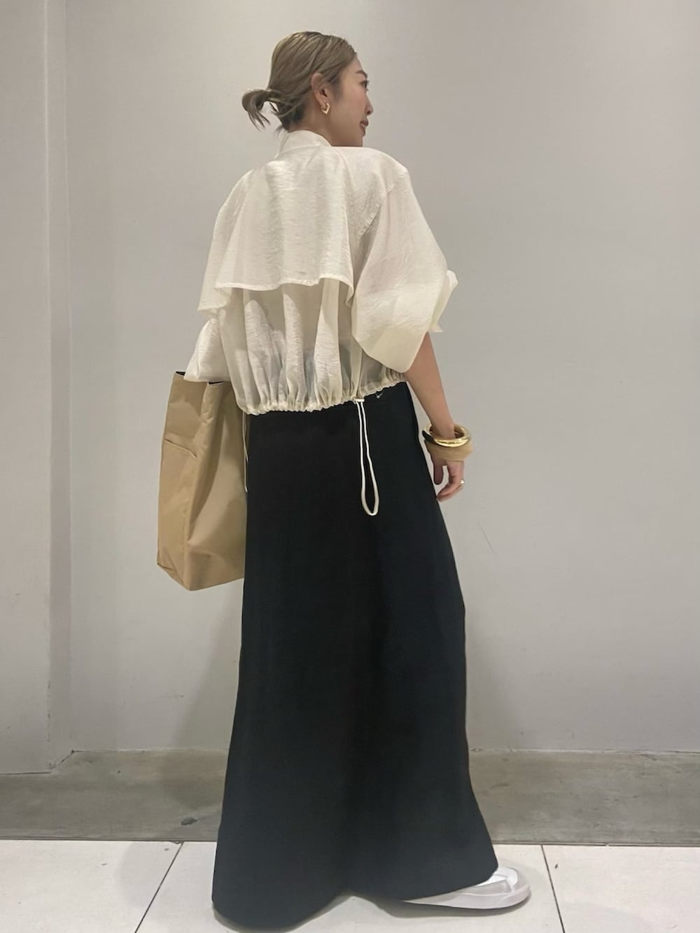 ベージュ系のトートバッグ、ベージュ系のブルゾン、ブラック系のスカートを着用したレディースの春コーディネートの3枚目の写真