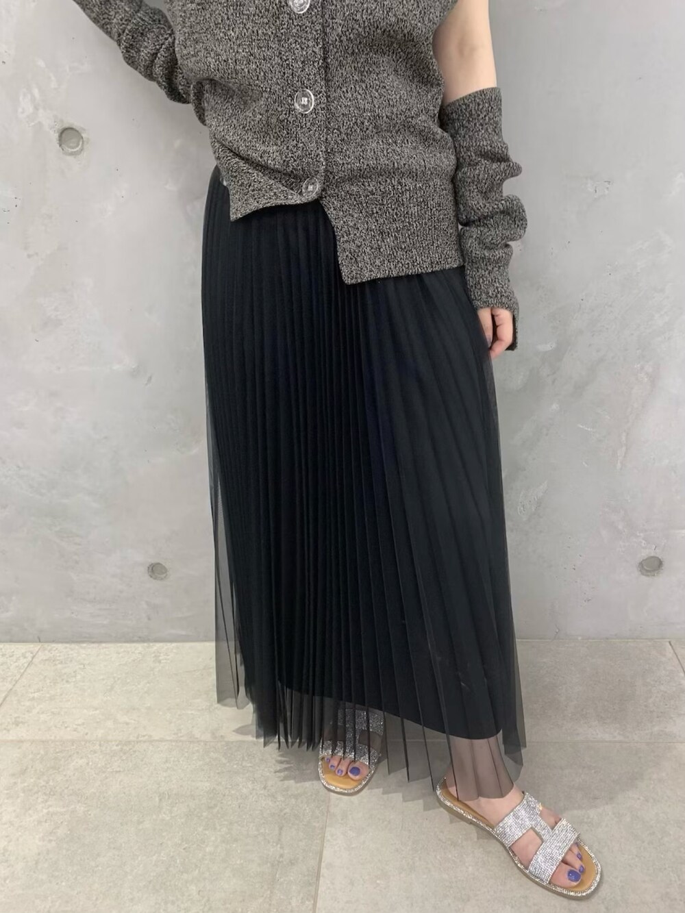 ブラウン系のカーディガン/ボレロ、ブラック系のスカート、シルバー系のサンダルを着用したレディースの春コーディネートの5枚目の写真