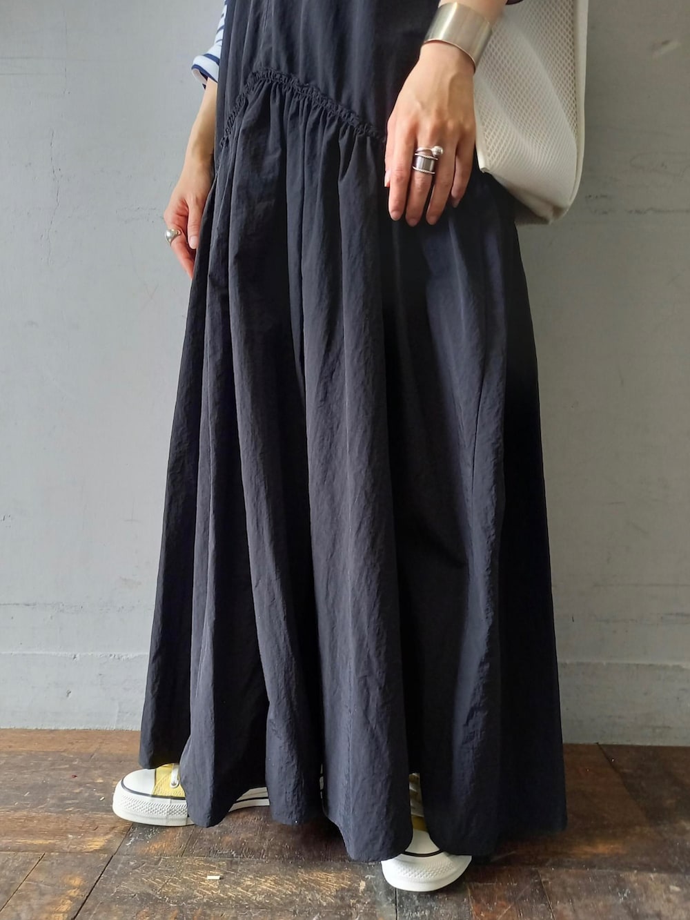 ブラック系のワンピース、ホワイト系のハンドバッグ、イエロー系のスニーカーを着用したレディースの春コーディネートの5枚目の写真