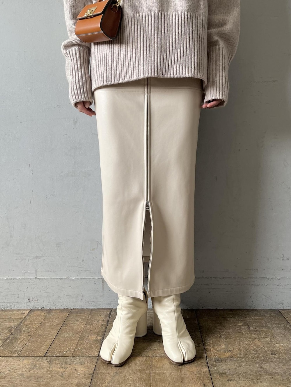 ベージュ系のニット/セーター、イエロー系のショルダーバッグ、ホワイト系のスカートを着用したレディースの夏コーディネートの5枚目の写真