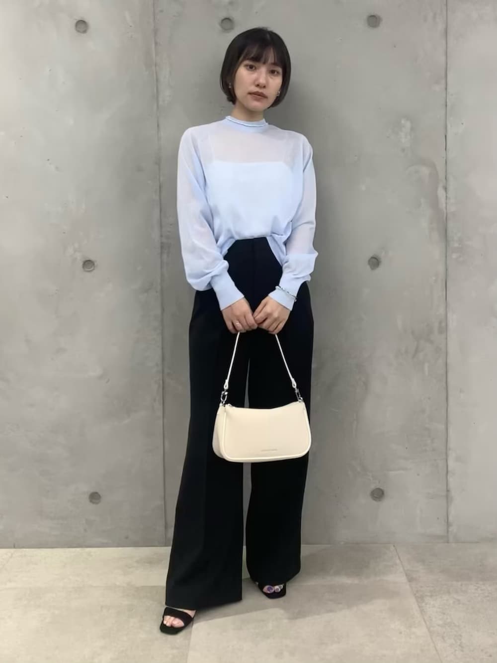 ブルー系のTシャツ/カットソー、ブラック系のスラックス、ホワイト系のショルダーバッグを着用したレディースの春コーディネートの2枚目の写真