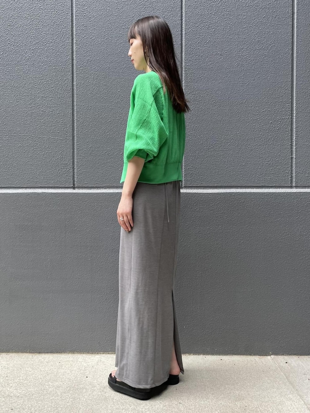 グリーン系のカーディガン/ボレロ、グレー系のワンピース、ブラック系のサンダルを着用したレディースの夏コーディネートの2枚目の写真