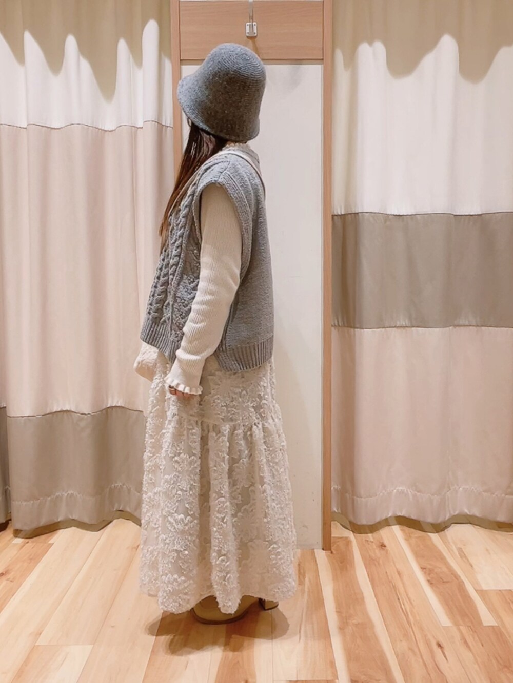 グレー系のニット/セーター、ホワイト系のハンドバッグ、ホワイト系のスカートを着用したレディースの冬コーディネートの2枚目の写真