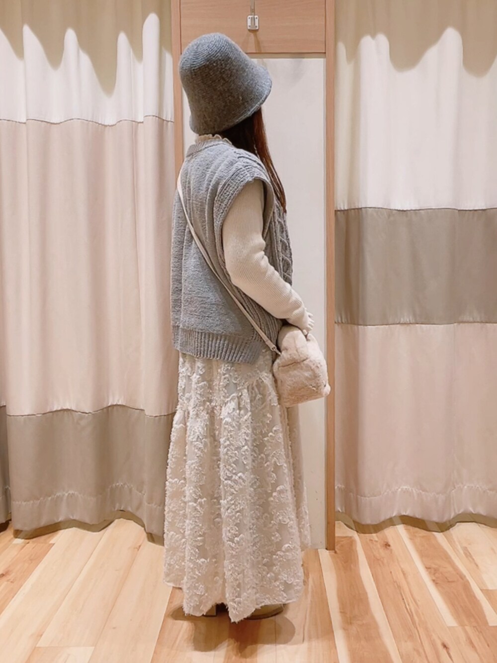 グレー系のニット/セーター、ホワイト系のハンドバッグ、ホワイト系のスカートを着用したレディースの冬コーディネートの4枚目の写真