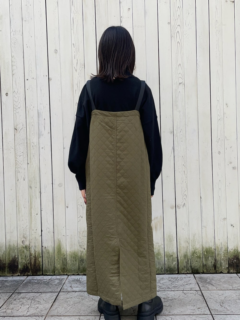 ブラック系のニット/セーター、グリーン系のジャンパースカート、ホワイト系のシャツ/ブラウスを着用したレディースの冬コーディネートの3枚目の写真
