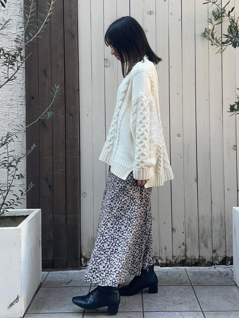 ホワイト系のニット/セーター、ホワイト系のTシャツ/カットソー、ブラック系のスカートを着用したレディースの冬コーディネートの2枚目の写真