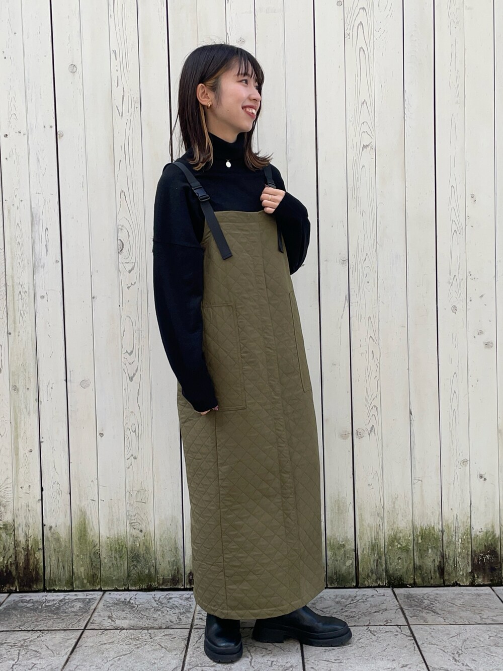 ブラック系のニット/セーター、グリーン系のジャンパースカート、ホワイト系のシャツ/ブラウスを着用したレディースの冬コーディネートの2枚目の写真