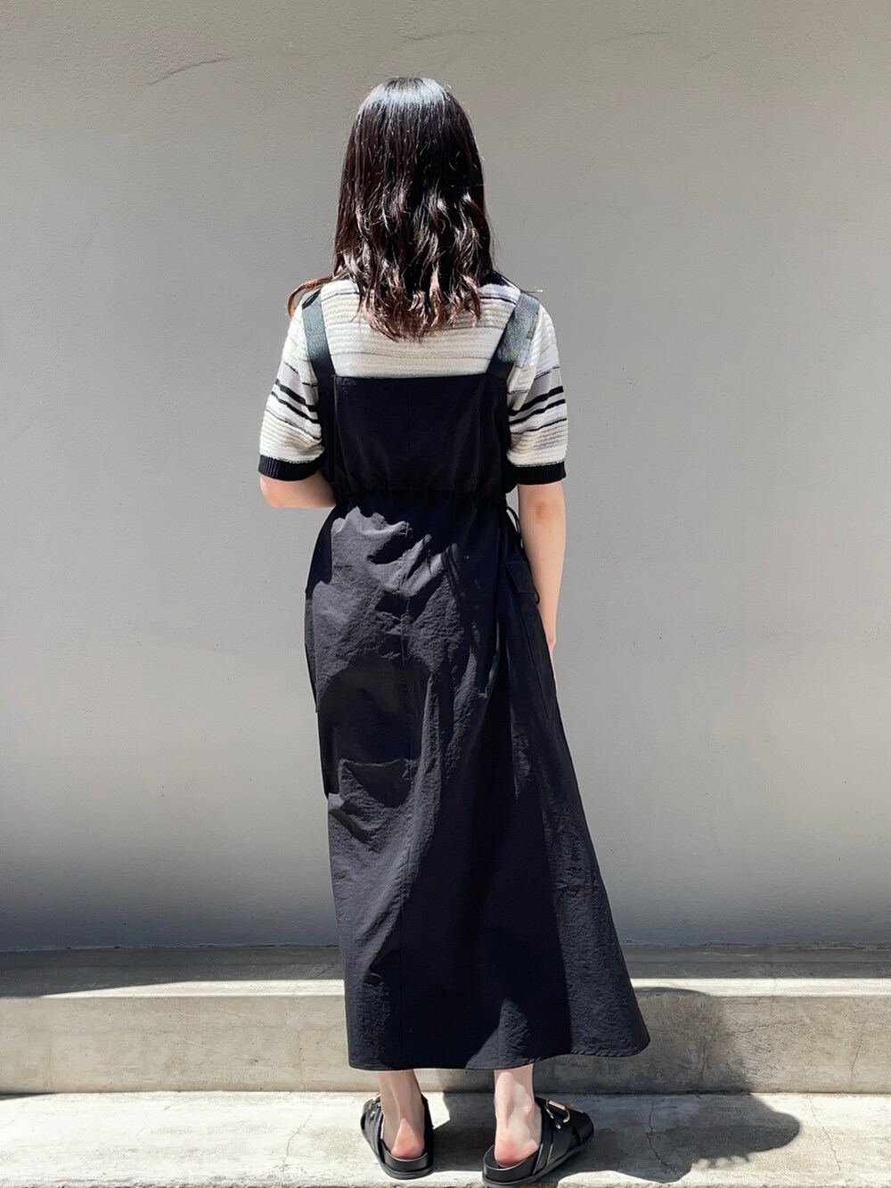 ブラック系のニット/セーター、ブラック系のワンピース、ブラック系のサンダルを着用したレディースの春コーディネートの2枚目の写真