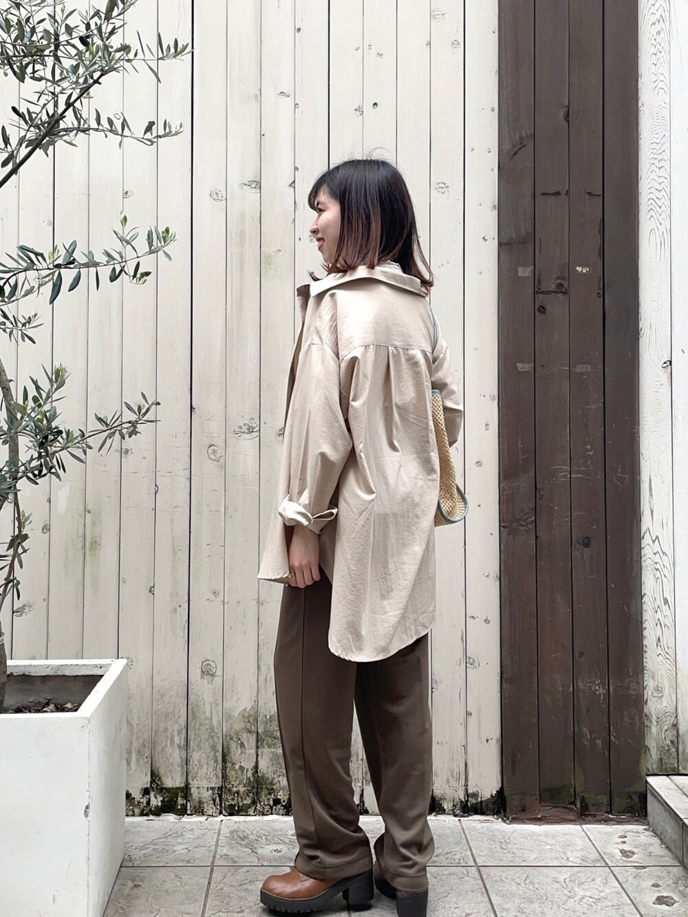 ホワイト系のシャツ/ブラウス、ブルー系のハンドバッグ、ブラウン系のパンツを着用したレディースの春コーディネートの2枚目の写真