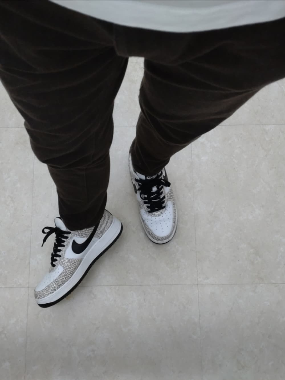 ホワイト系のスニーカー、ブラウン系のパンツ、ホワイト系のTシャツ/カットソーを着用したメンズの春コーディネートの3枚目の写真