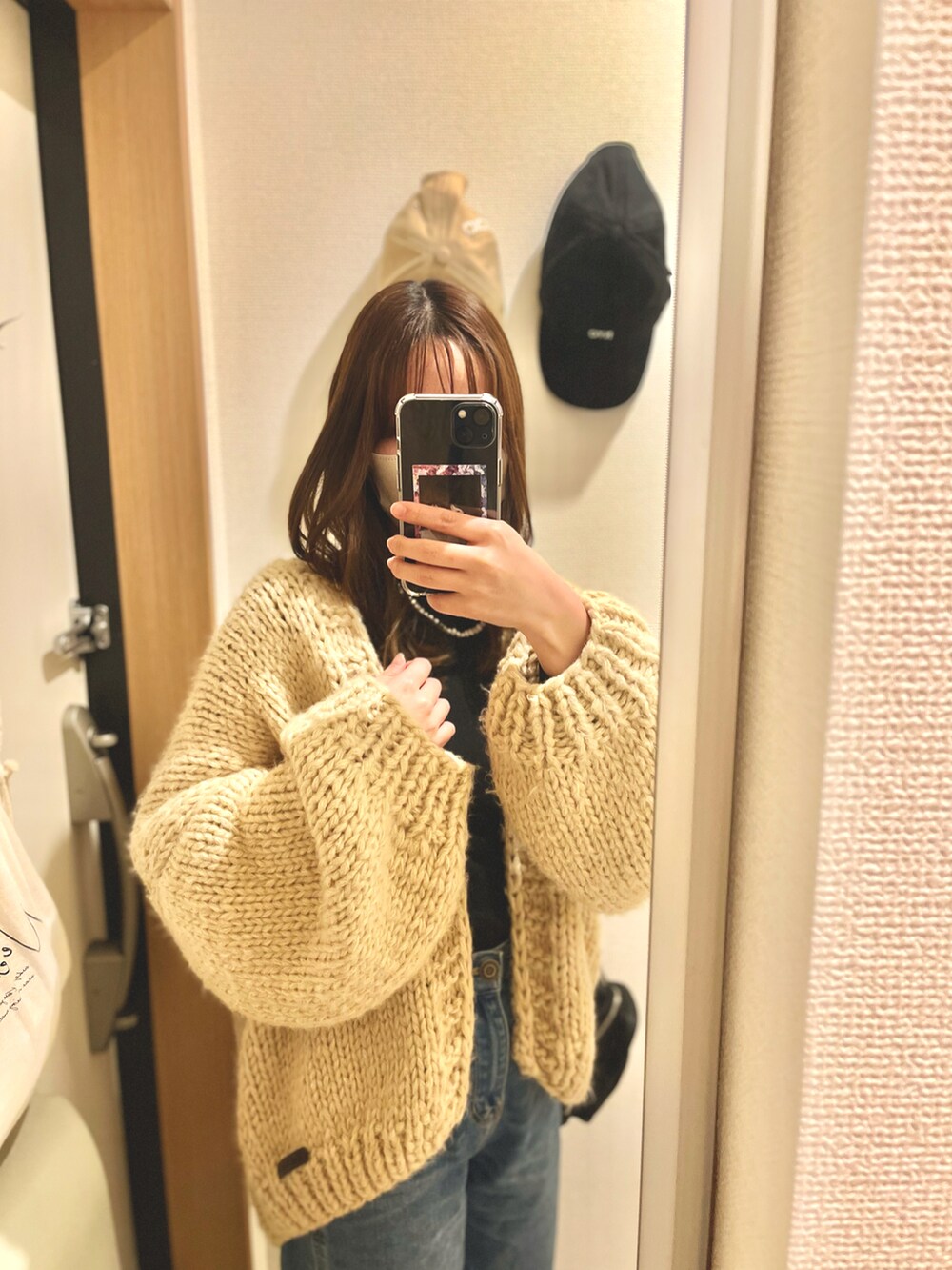 ブルー系のデニムパンツ、ベージュ系のカーディガン/ボレロ、ホワイト系のネックレスを着用したレディースの冬コーディネートの2枚目の写真