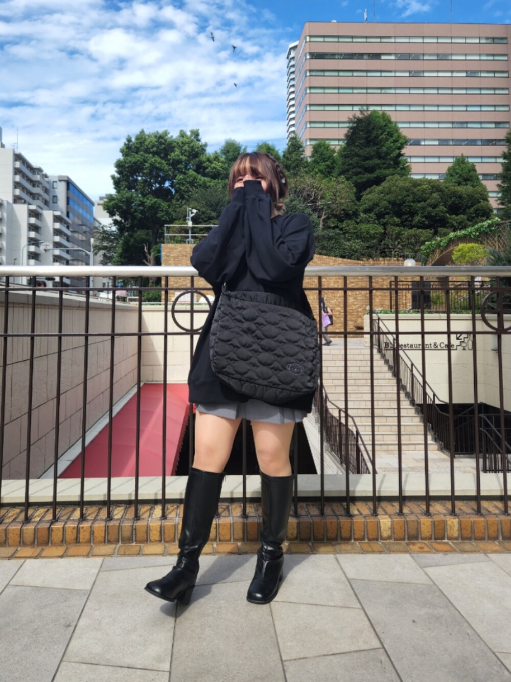 ブラック系のスウェット、ブラック系のショルダーバッグ、ブラック系のブーツを着用したレディースの秋コーディネートの2枚目の写真