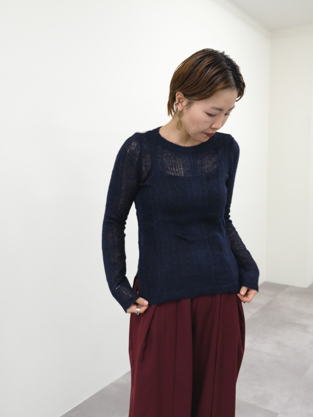 ブルー系のニット/セーター、レッド系のスラックスを着用したレディースの秋コーディネートの3枚目の写真