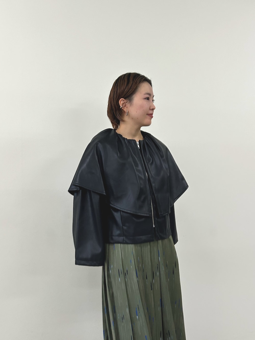 ブラック系のライダースジャケット、グリーン系のスカートを着用したレディースの秋コーディネートの2枚目の写真