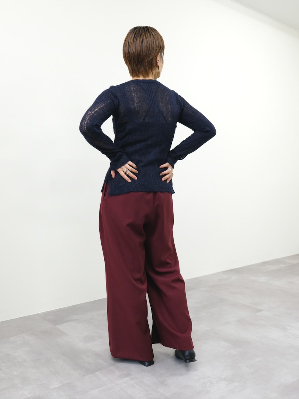 ブルー系のニット/セーター、レッド系のスラックスを着用したレディースの秋コーディネートの2枚目の写真