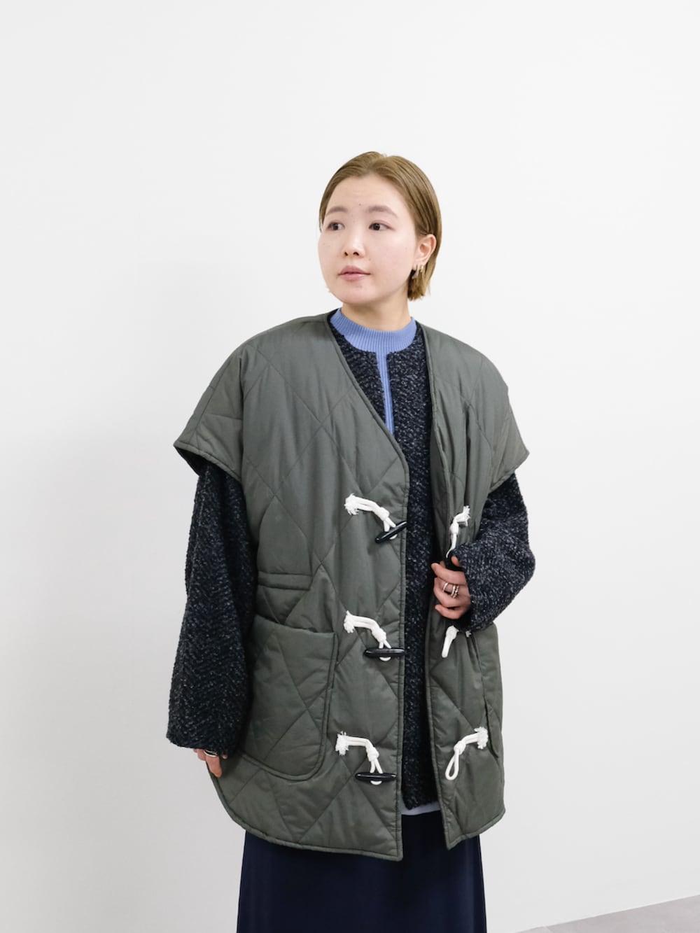 ブルー系のスカート、グレー系のカーディガン/ボレロ、ブルー系のニット/セーターを着用したレディースの冬コーディネートの2枚目の写真