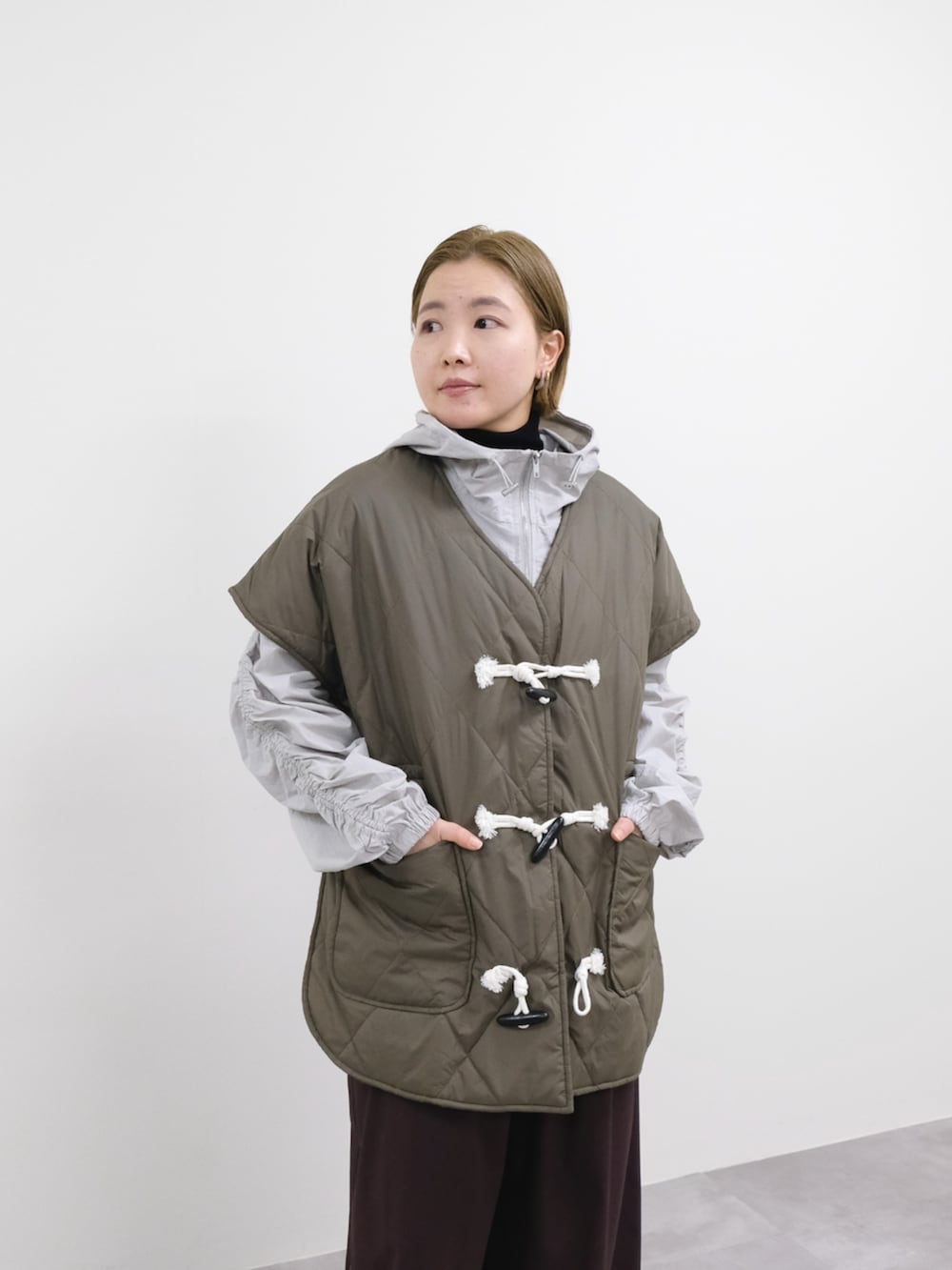 ブラウン系のスラックス、グレー系のベストを着用したレディースの冬コーディネートの3枚目の写真