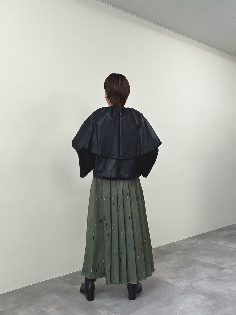 ブラック系のライダースジャケット、グリーン系のスカートを着用したレディースの秋コーディネートの4枚目の写真