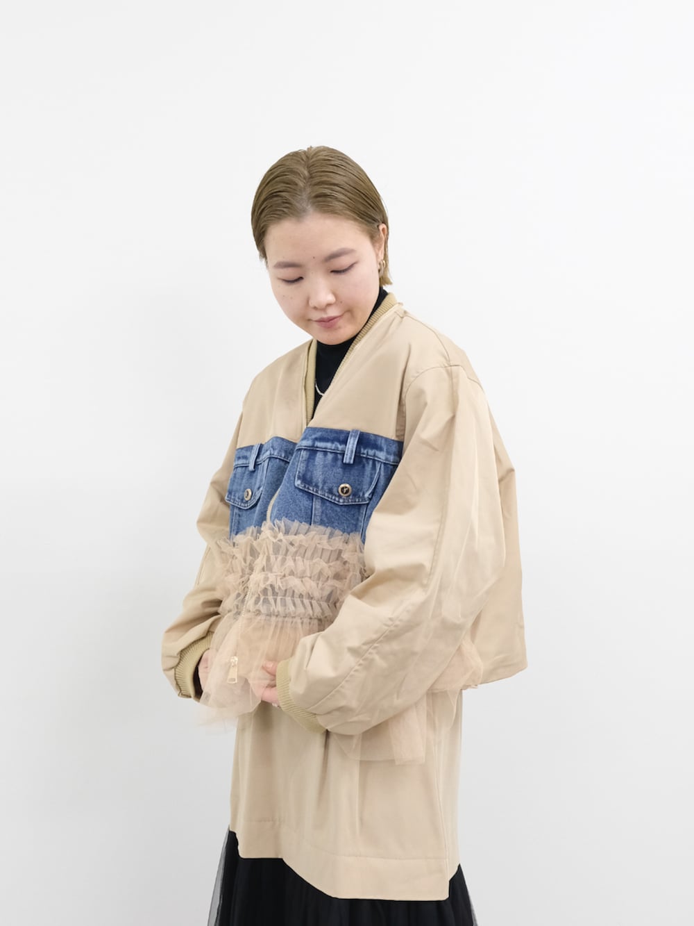 ベージュ系のスカート、ベージュ系のMA-1、ブラック系のニット/セーターを着用したレディースの冬コーディネートの3枚目の写真