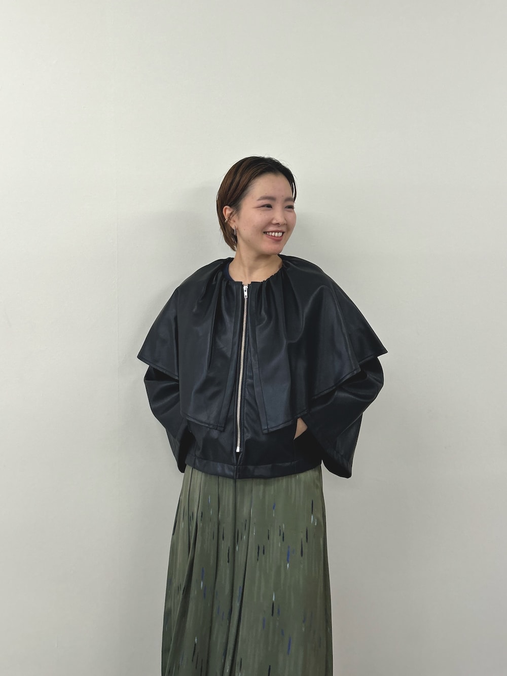 ブラック系のライダースジャケット、グリーン系のスカートを着用したレディースの秋コーディネートの3枚目の写真