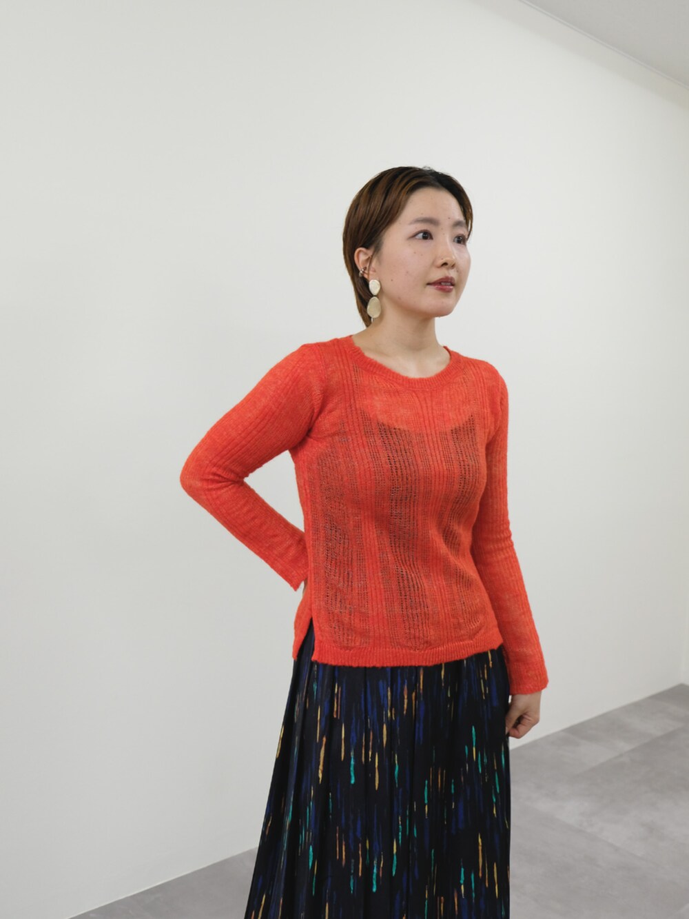 オレンジ系のニット/セーター、ブラック系のスカートを着用したレディースの秋コーディネートの3枚目の写真