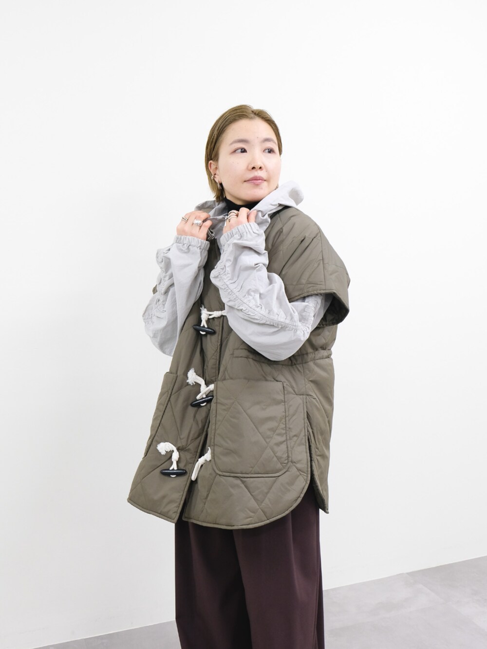 ブラウン系のスラックス、グレー系のベストを着用したレディースの冬コーディネートの2枚目の写真